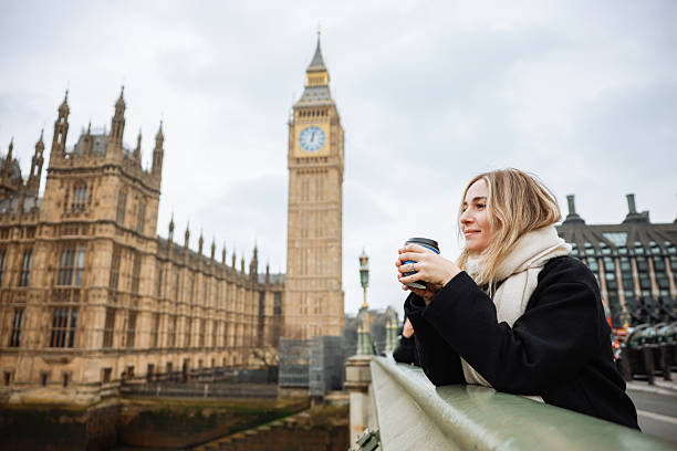 istock Young woman drinking coffee in a disposable cup on Westminster Bridge 2211935020