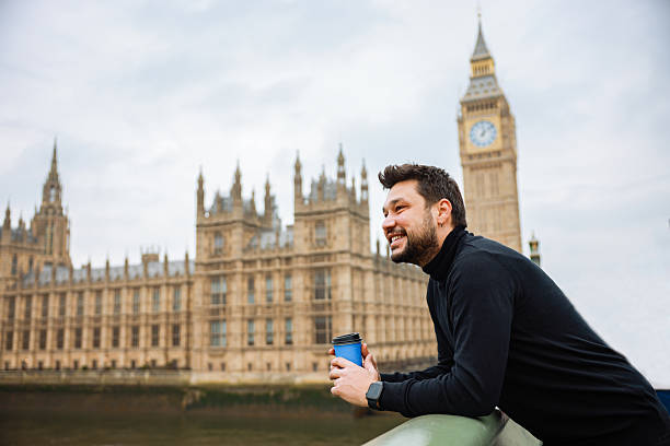 istock Young man drinking coffee in a disposable cup on Westminster Bridge 2211936222