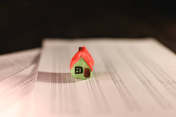 istock Small toy house stands on financial documents symbolizing investment 2211936241