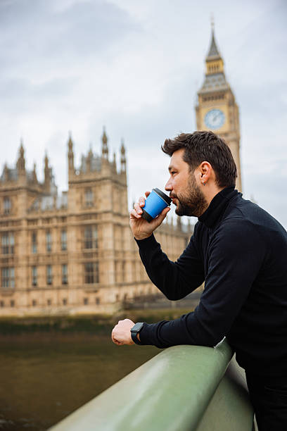 istock Young man drinking coffee in a disposable cup on Westminster Bridge 2211936644