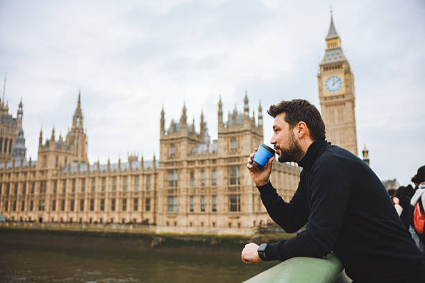 istock Young man drinking coffee in a disposable cup on Westminster Bridge 2211937340