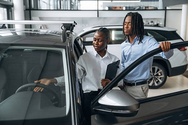 istock Doors are opened, looking inside. Car seller is assisting client in the automobile salon 2211942179