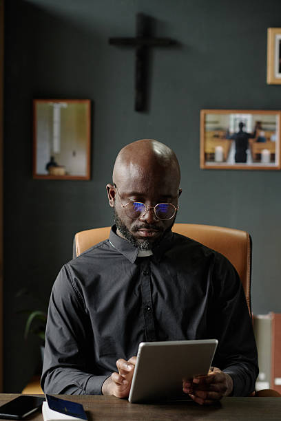 Pastor with Tablet in Hands Sitting in Office