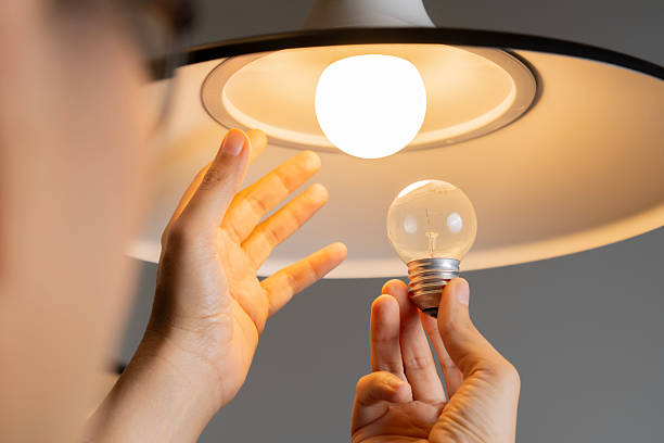 istock Hands replacing a light bulb in a minimalist room, with focus on the bulb and the clean light fixture 2211946864