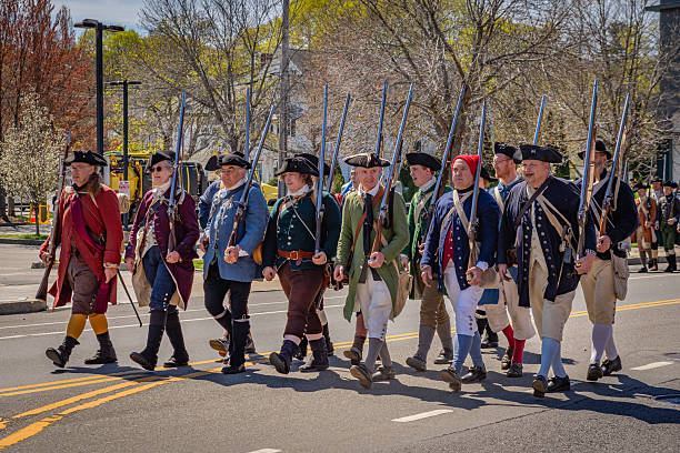 Arlington, MA, US-April 20, 2025: Battle of Menotomy 250th Reenactment - patriotic colonialists fight British soldiers on Massachusetts Avenue.