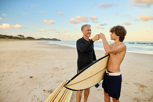 istock Father and son putting on wetsuits before surfing at the beach 2211947003
