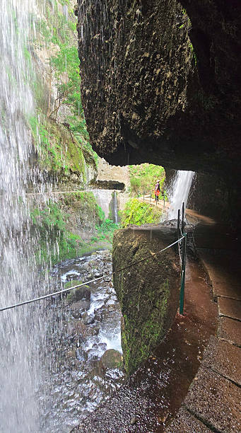 istock Walkway under waterfalls at Levada Do Moinho, Madeira 2211948275