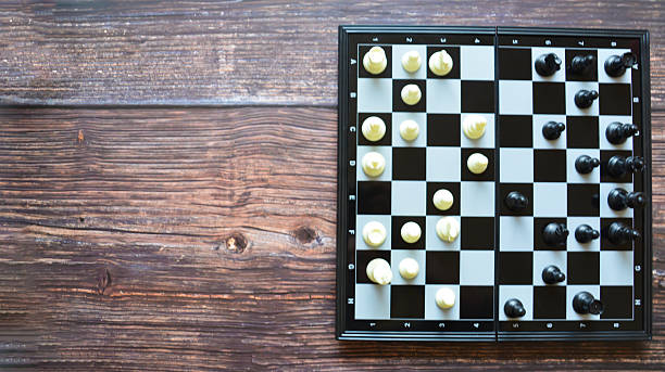 istock Chessboard with chess pieces on the wooden table. Black chessboard. Chess pieces on the board. Chess game 2211948827