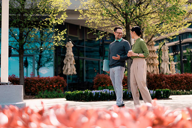 istock Two colleagues walking and talking during their coffee break 2211951068
