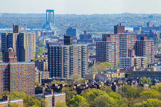 Aerial view of apartment buildings in the Bronx, New York City, with the Bronx-Whitestone Bridge in the background. High angle view of brick apartments rising above trees in springtime in NYC