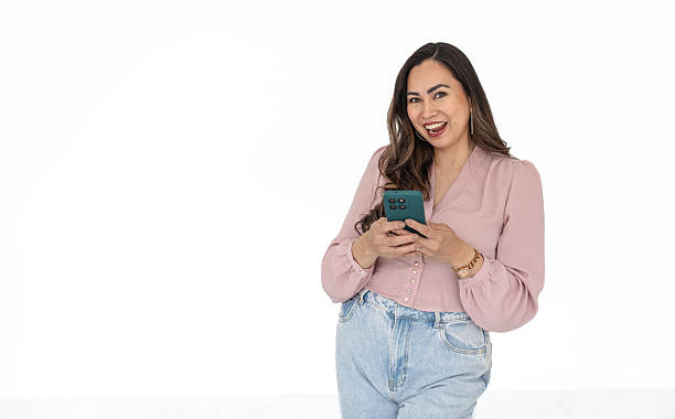 istock Young woman smiles while interacting with a mobile app on her smartphone against a blank white backdrop 2211956719