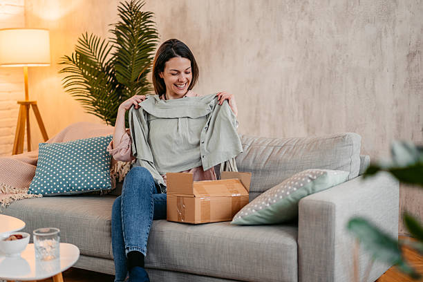 istock Young Woman Unboxing A Package With A New Button Down Shirt She Ordered Online 2211960360