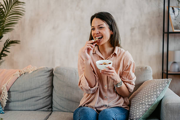 istock Young Woman Eating Cookies While Sitting On The Sofa 2211961846