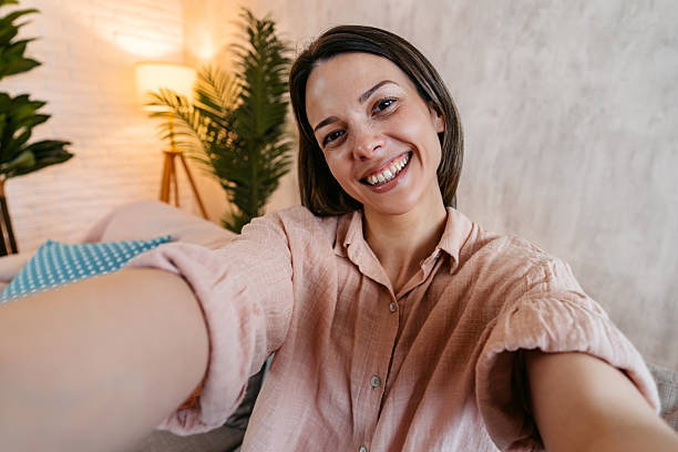 istock Young Woman Taking Selfies While Sitting On The Sofa At Home 2211962407