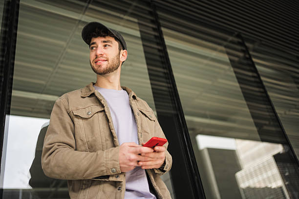 Young man using mobile phone and looking away in the city