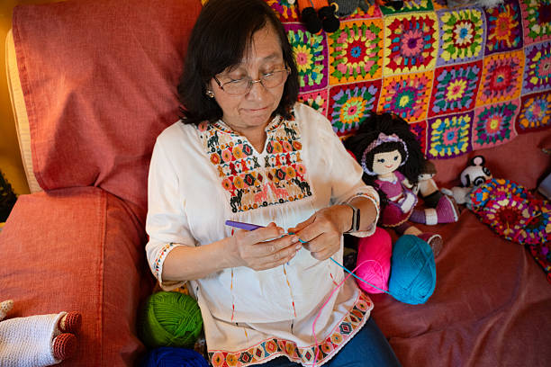 In a cozy, color-filled living room, a cheerful woman engages in knitting, with bright handmade decorations enhancing the vibrant and welcoming atmosphere.