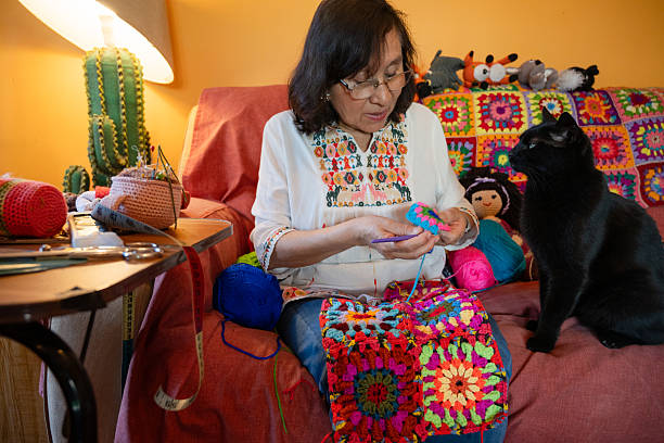 Senior Woman Knitting Crochet While Sitting On Chair Against White Background