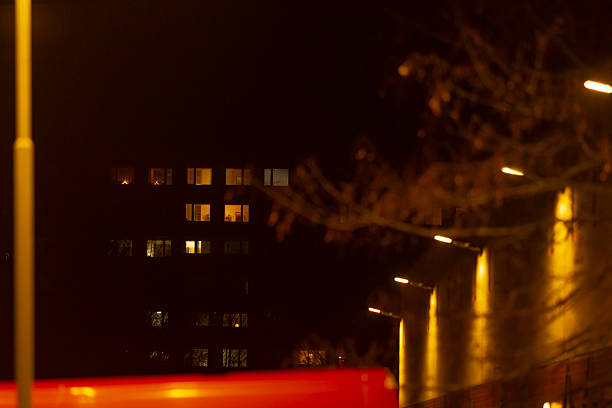 A dimly lit urban environment beautifully showcasing the glowing illuminated apartment windows that brighten the night sky