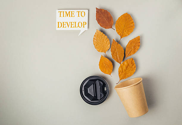 istock Cup with a leaf on it and the words Time to develop written on it 2211971562