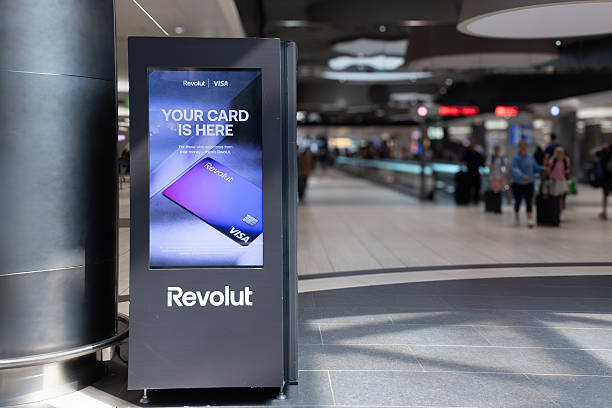 Digital signage displaying credit card of online bank Revolut advertisement in busy airport terminal Airport, Fiumicino, Rome,Italy - 30 July 2024: Modern digital signage displaying a vibrant credit card of online bank Revolut advertisement in a bustling airport terminal, retail digital signage stock pictures, royalty-free photos & images