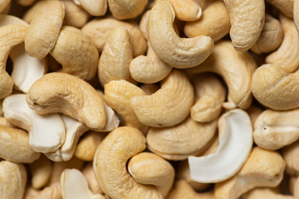 A detailed close-up of raw cashew nuts scattered in an abstract pattern, showcasing their natural textures and tones, ideal for concepts of health and nutrition.