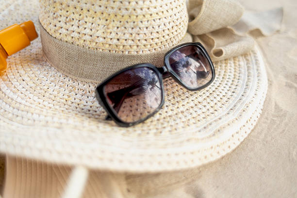 istock Summer essentials including sunglasses and a straw hat on a sandy beach during a sunny day 2211972327