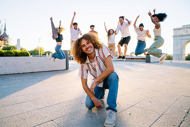 istock Young man kneeling with friends jumping in the background 2211976734