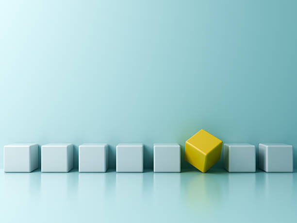 istock Stand out from the crowd and different concepts One strange yellow cube square box amongs other light blue boxes on light blue green pastel color background with reflections and shadows 3D rendering 2211980154