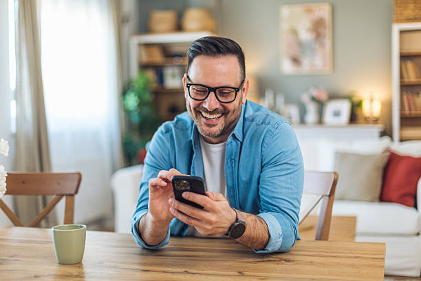 istock Happy man using smartphone and smiling at home 2211982634