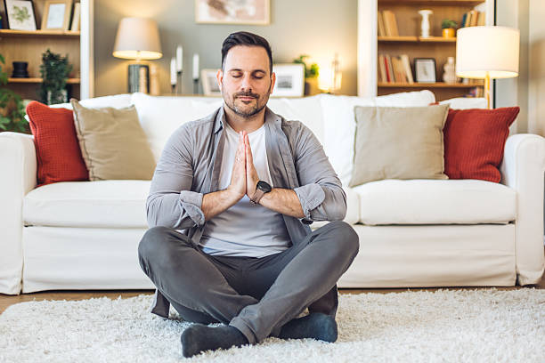 istock Serene man meditating in lotus position at home 2211984693