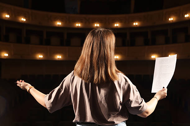 Professional actress rehearsing on stage in theatre, back view