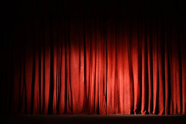 istock Elegant closed red curtains illuminated by spotlight in theatre 2211986951