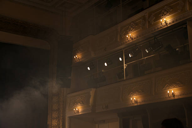 A backstage view showing technical equipment racks, cables, and lighting in a concert or event setting. The image highlights the behind-the-scenes infrastructure required for a live performance.