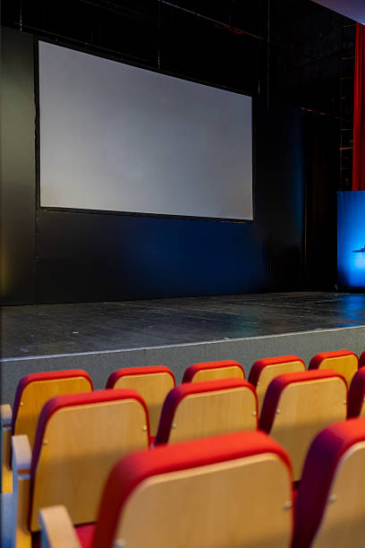 istock Modern theater stage with empty seats and a large projection screen in a well-lit auditorium setting 2211990065