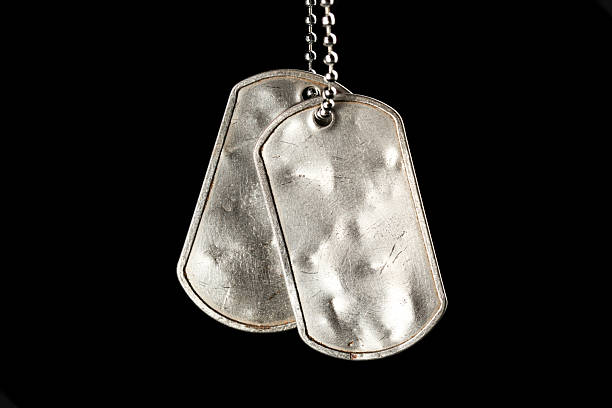 istock Old and worn blank military dog tags isolated on black 2211995956