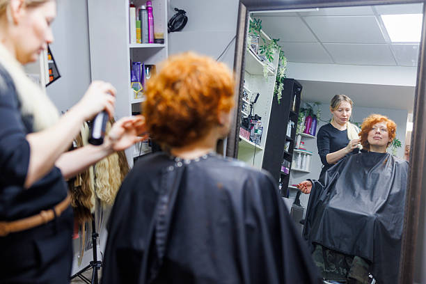 istock Ginger transformation at modern salon. Stylist cuts vibrant curls while client observes in mirror. 2212012211