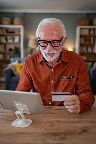 istock Senior man making online payment using digital tablet and credit card at home 2212012810