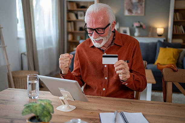 istock Happy senior man making online payment using tablet and credit card at home 2212012852