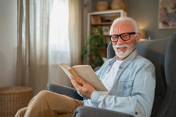 istock Senior man reading a book and smiling at home 2212012860