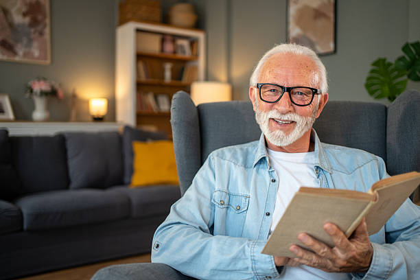 istock Senior man reading a book and smiling at home 2212012934