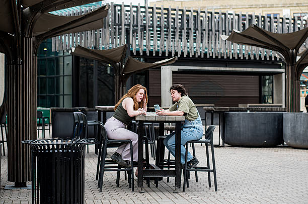 istock Non-Binary Partner and Redhead Girlfriend Connect Over Phone at picnic table 2212013301