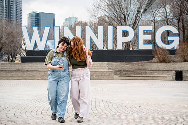 istock Non-Binary Partner and Redhead Girlfriend Stroll Through Downtown Winnipeg, Sharing a Moment 2212013303