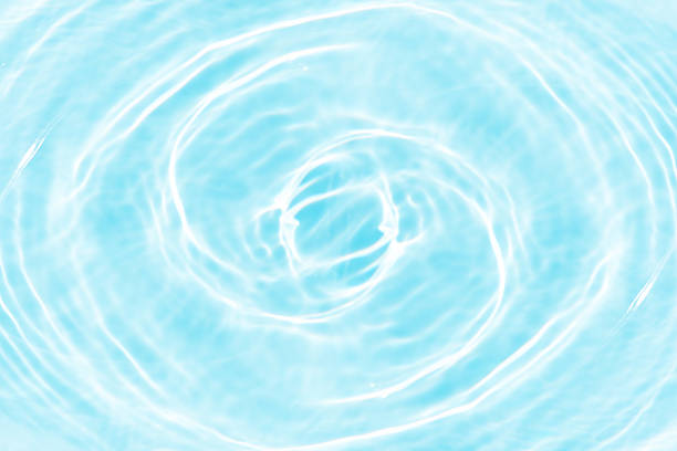 Blue water with ripples on the surface. Defocus blurred transparent blue colored clear calm water surface texture with splashes and bubbles. Water waves with shining pattern texture background.
