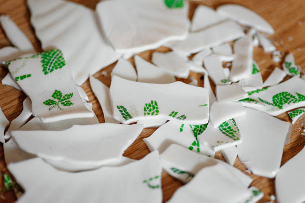 fragments of broken white and green plate on floor, broken dishes concept