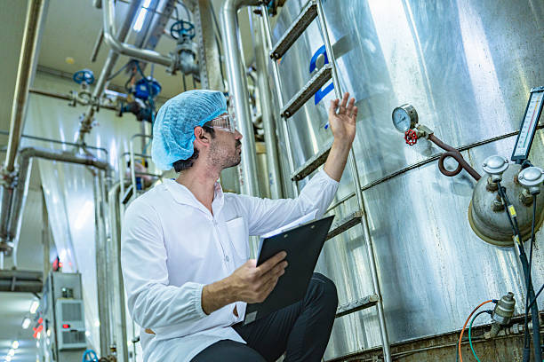istock Technician in protective gear evaluating a production tank, representing quality assurance, meticulous processes, and expertise in industrial manufacturing. 2212027824