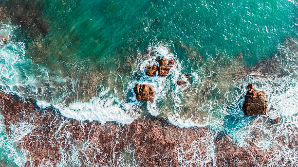 istock High angle drone view of blue waves hitting cliffs. Scenic nature background for summer content. 2212029988