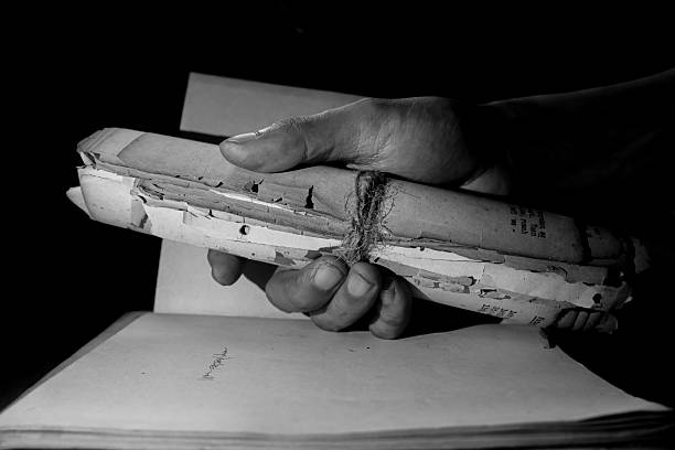 istock Person's hand holding an old roll of paper 2212033036