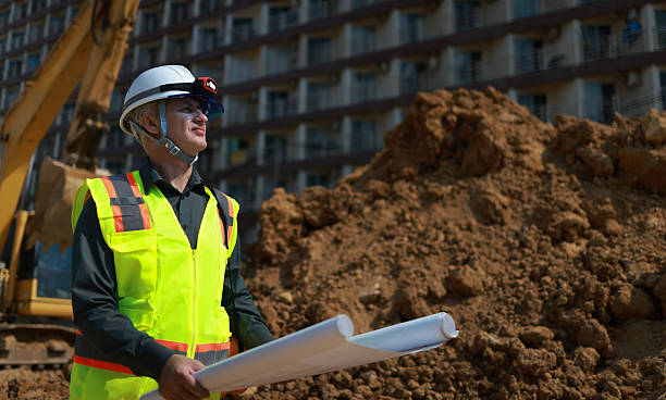 istock Civil engineer or site construction engineer with safety PPE, holding drawings, working on site 2212036427
