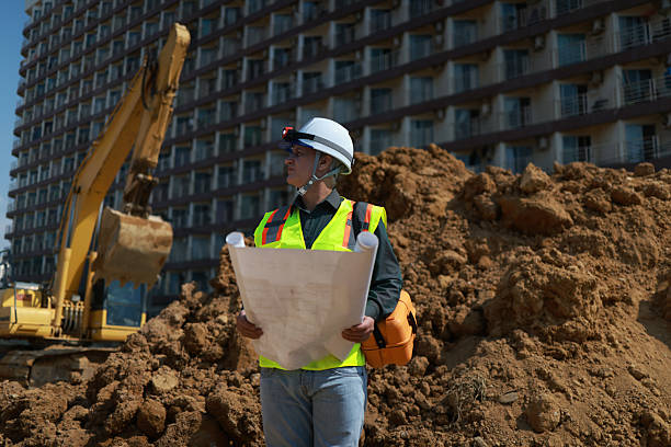 istock Civil engineer or site construction engineer with safety PPE, holding drawings, working on site 2212036431