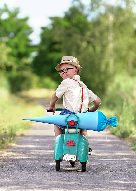 istock cheerful boy riding his scooter on the way to school 2212045510